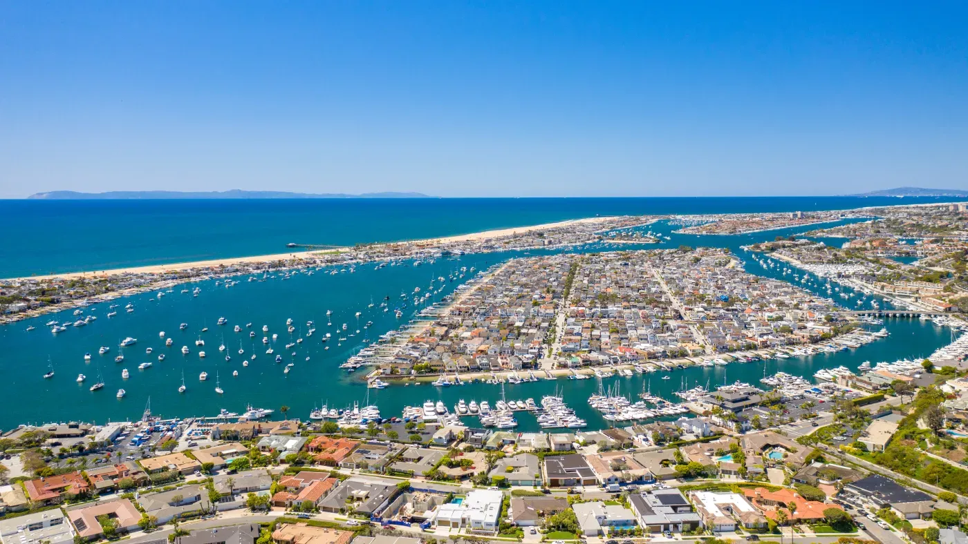Aerial view of a bustling coastal city harbor filled with numerous boats and residential areas.