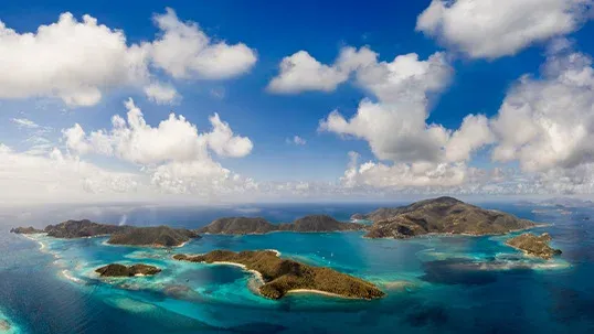 Aerial view of a tropical island archipelago with turquoise water and scattered clouds.