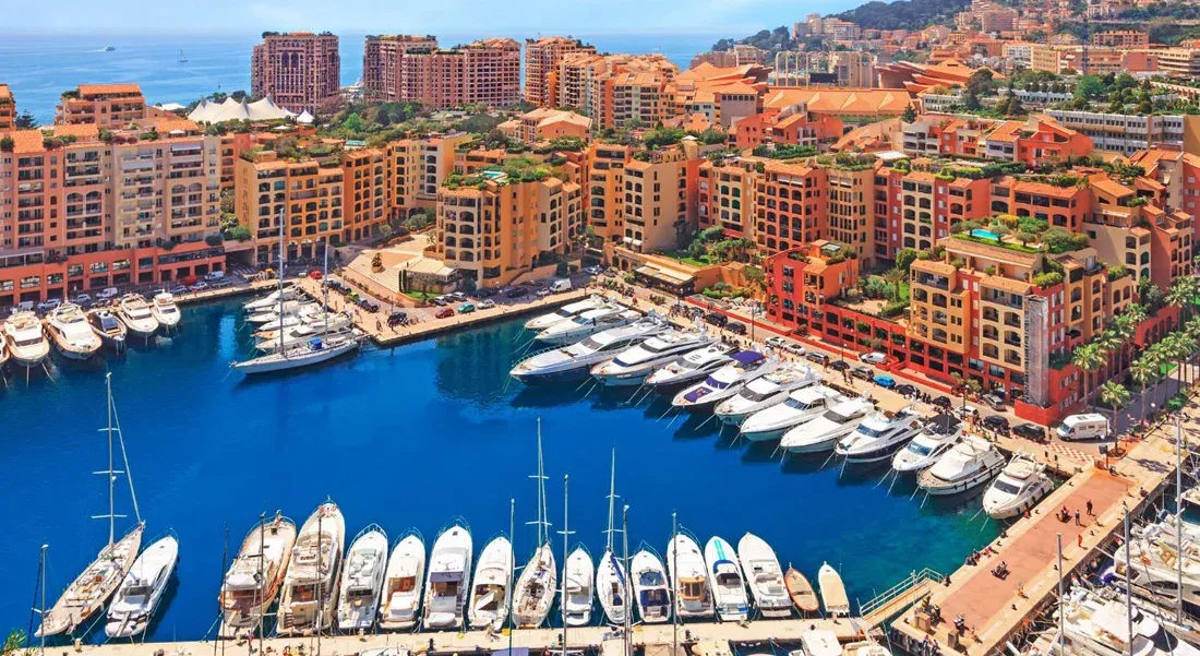 A panoramic view of a luxurious coastal city marina filled with many yachts and buildings.