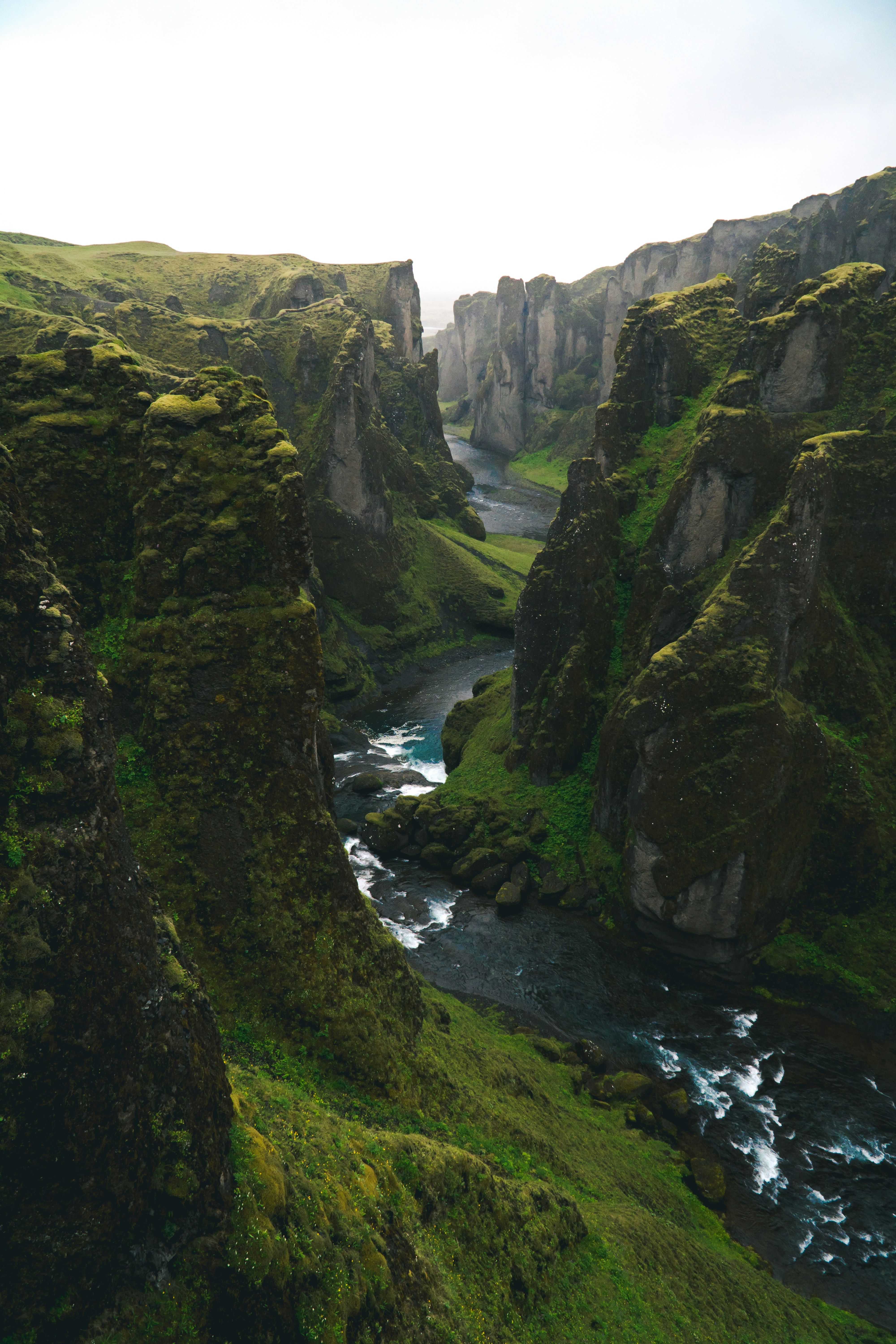 A deep canyon with a river flowing through lush green, rocky walls.