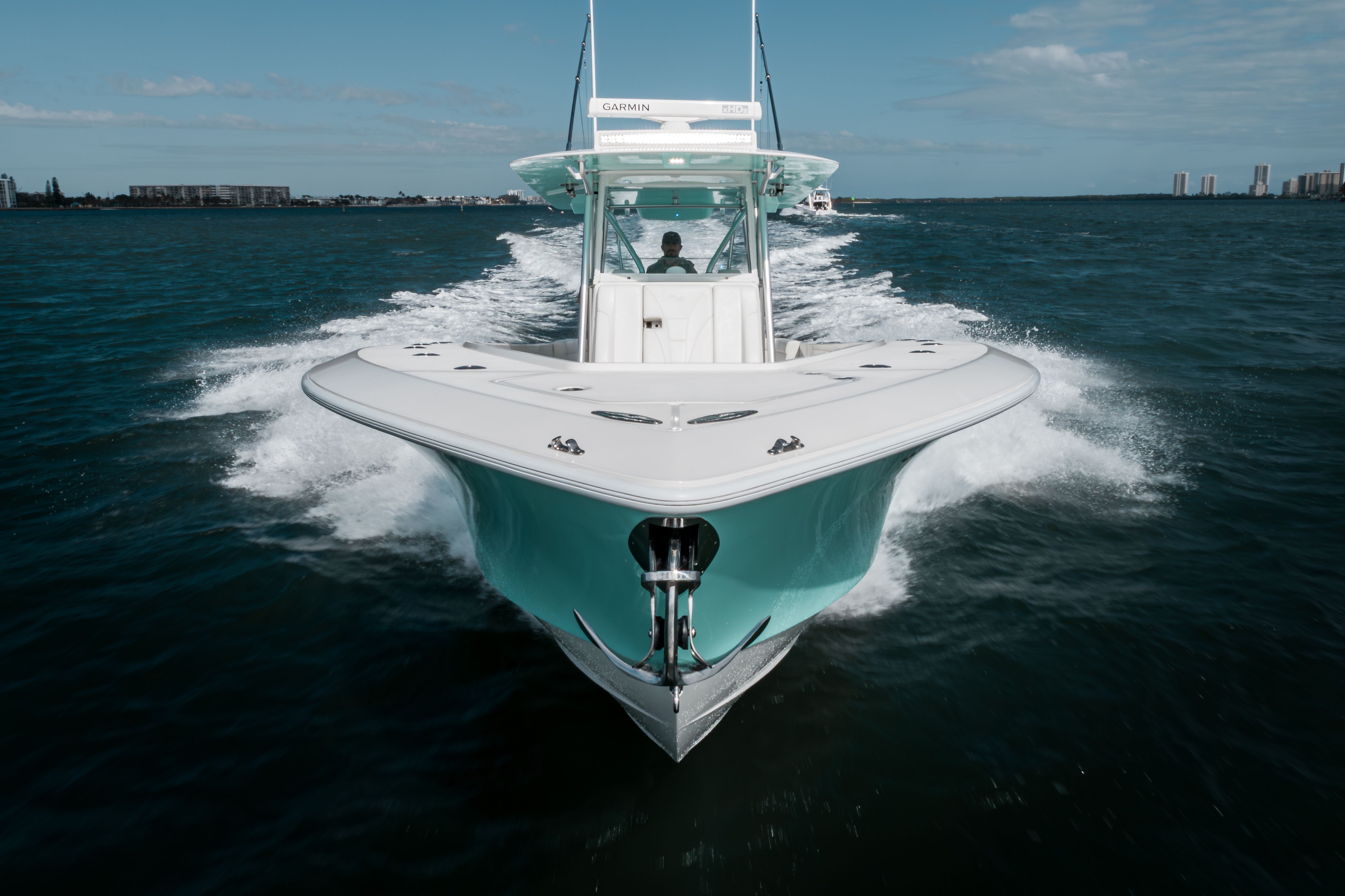 White and turquoise center console boat speeding across deep blue water, leaving a large wake.