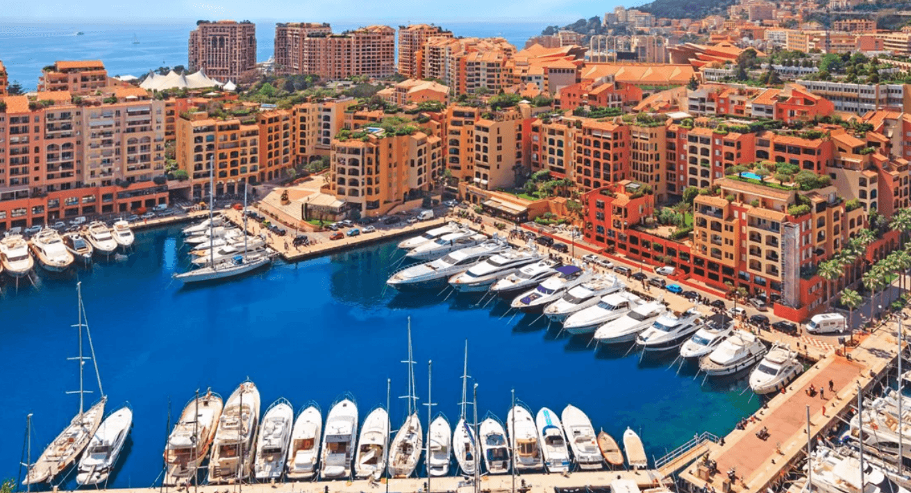 Aerial view of a vibrant marina filled with luxury yachts and colorful buildings in Monaco.
