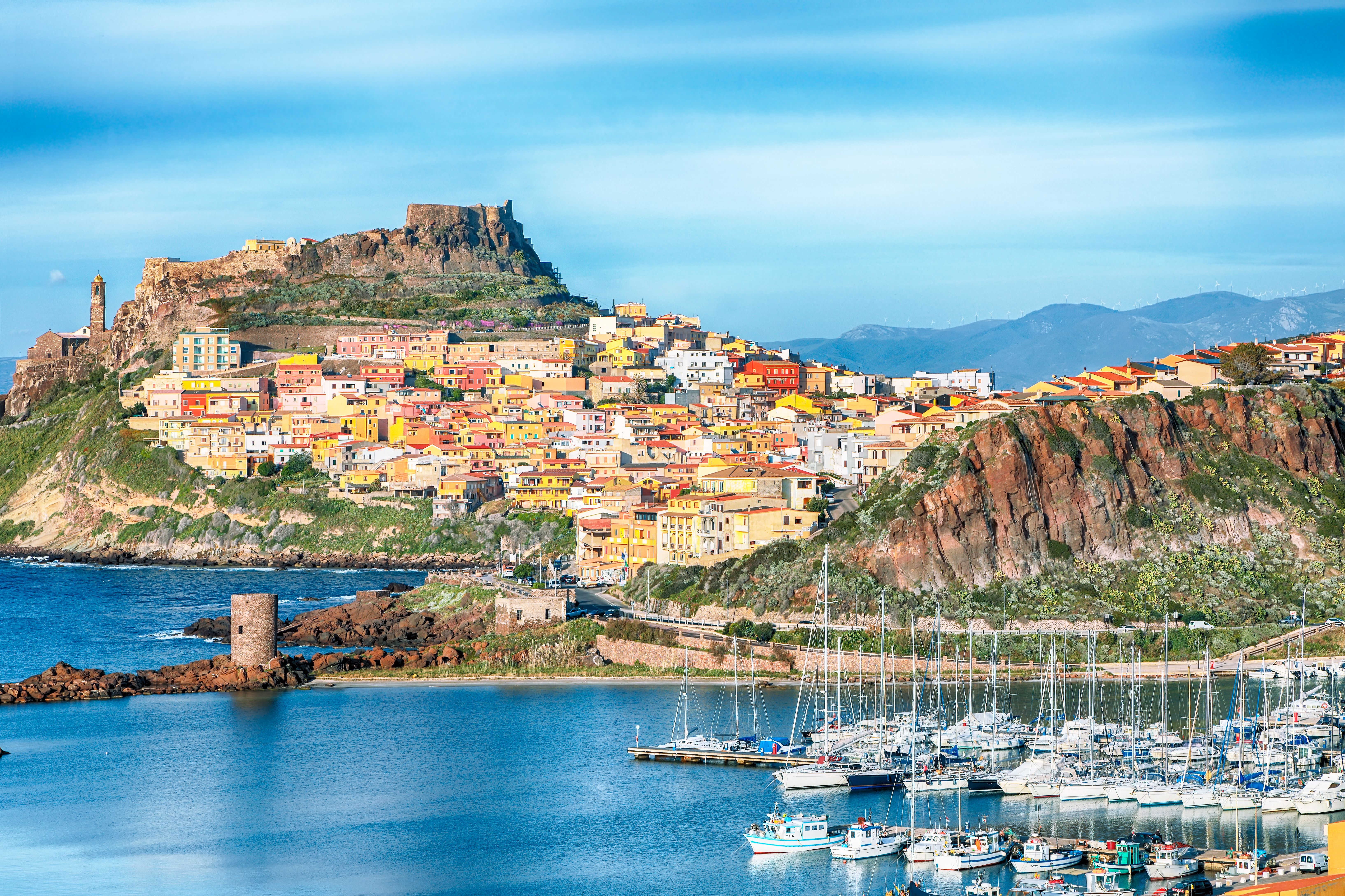 Vibrant coastal town on a rocky hill, featuring a harbor and historic castle.