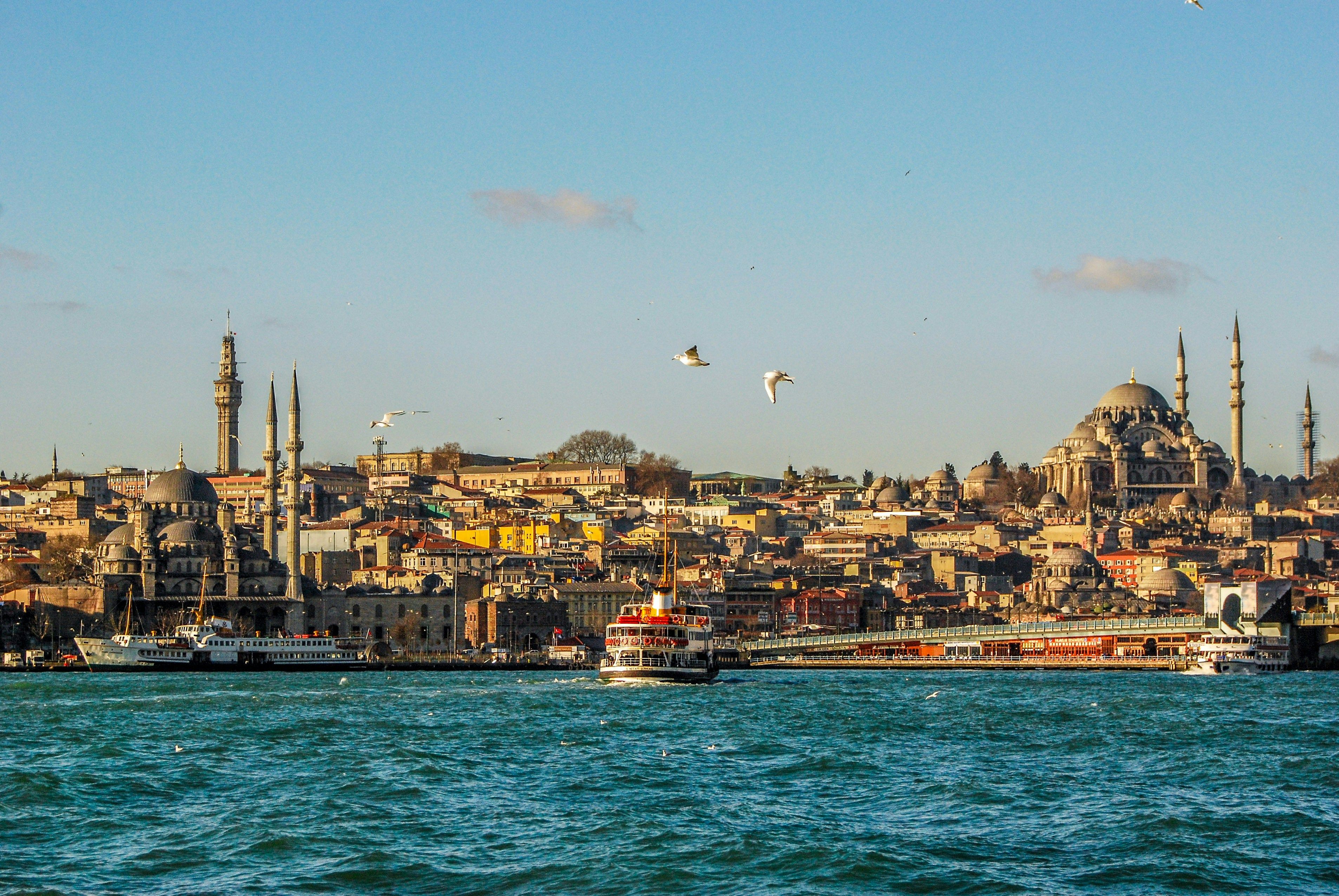 Historic Istanbul cityscape viewed from the Bosphorus with mosques, boats, and clear skies.