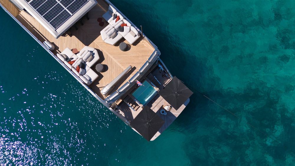Modern superyacht with a couple enjoying dinner on its extended side deck.