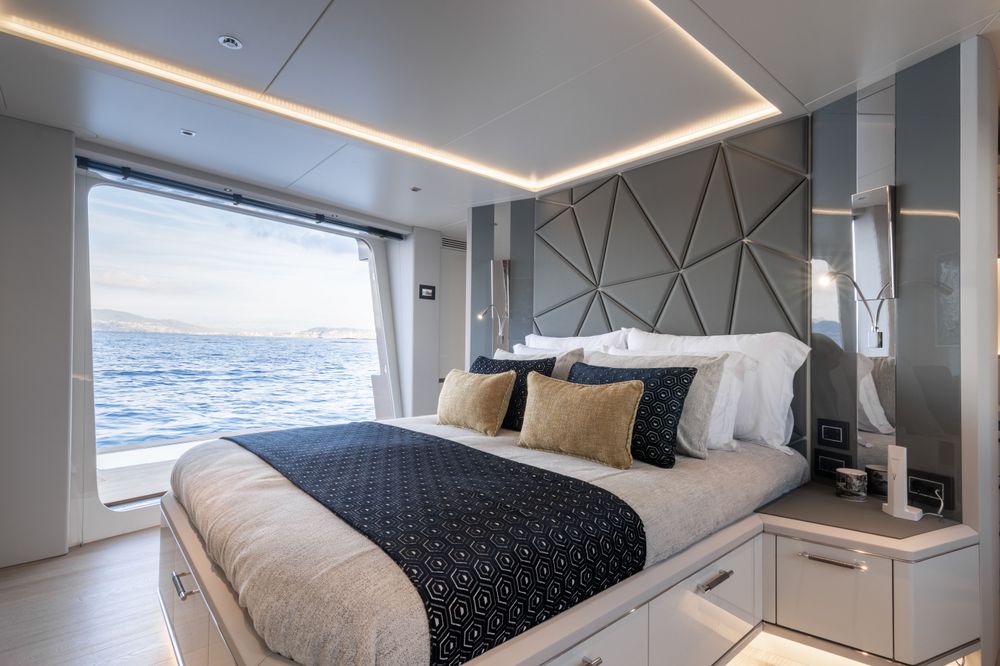 A luxurious yacht bedroom featuring a large bed, modern headboard, and expansive ocean view.