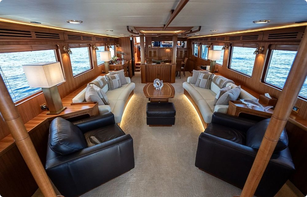 Luxurious yacht interior with comfortable sofas, armchairs, coffee table, and large ocean view windows.