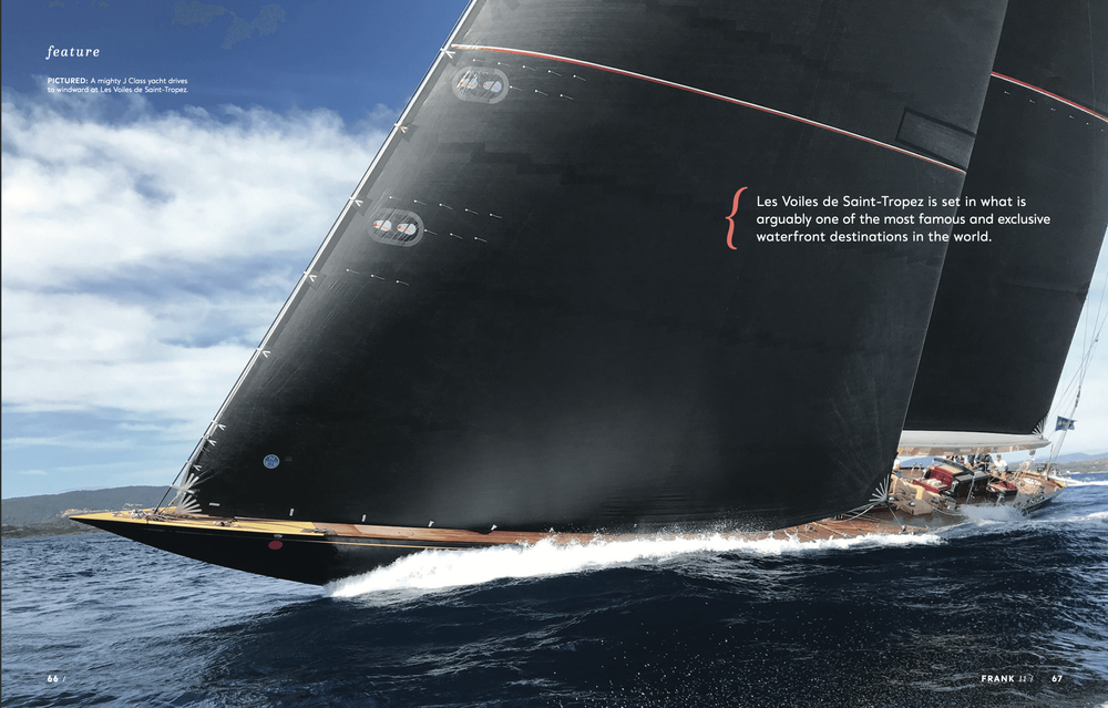 Large black-sailed yacht glides across blue water, creating a white wake.