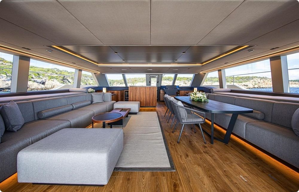 Luxurious yacht interior with a spacious lounge, dining area, wooden floor, and large windows.