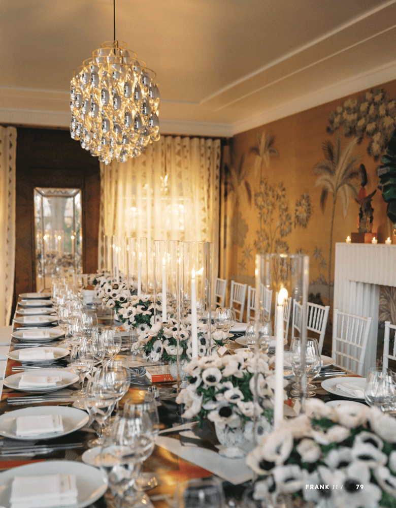 Elegant dining table set for a formal event with white flowers, candles, and a crystal chandelier.