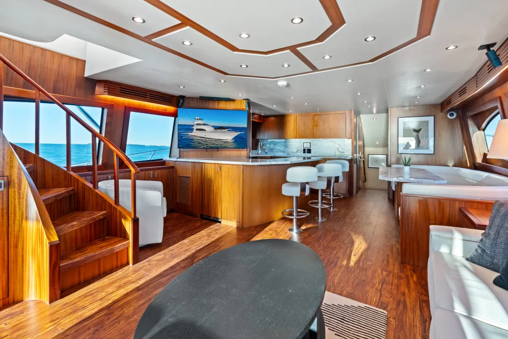Spacious luxury yacht interior with living area, bar, wooden staircase, and ocean view windows.
