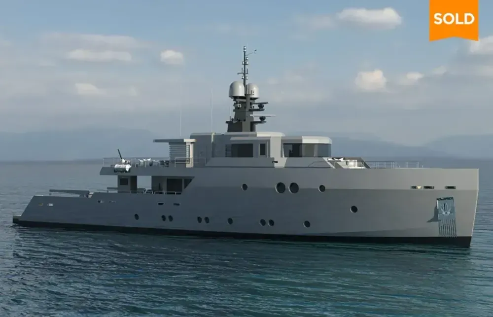 Sleek, modern grey yacht sailing on calm blue waters under a partly cloudy sky, marked SOLD.