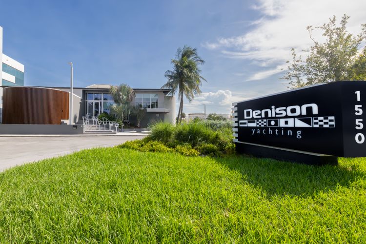 Denison Yachting office building with a prominent black sign and green landscaped entrance.