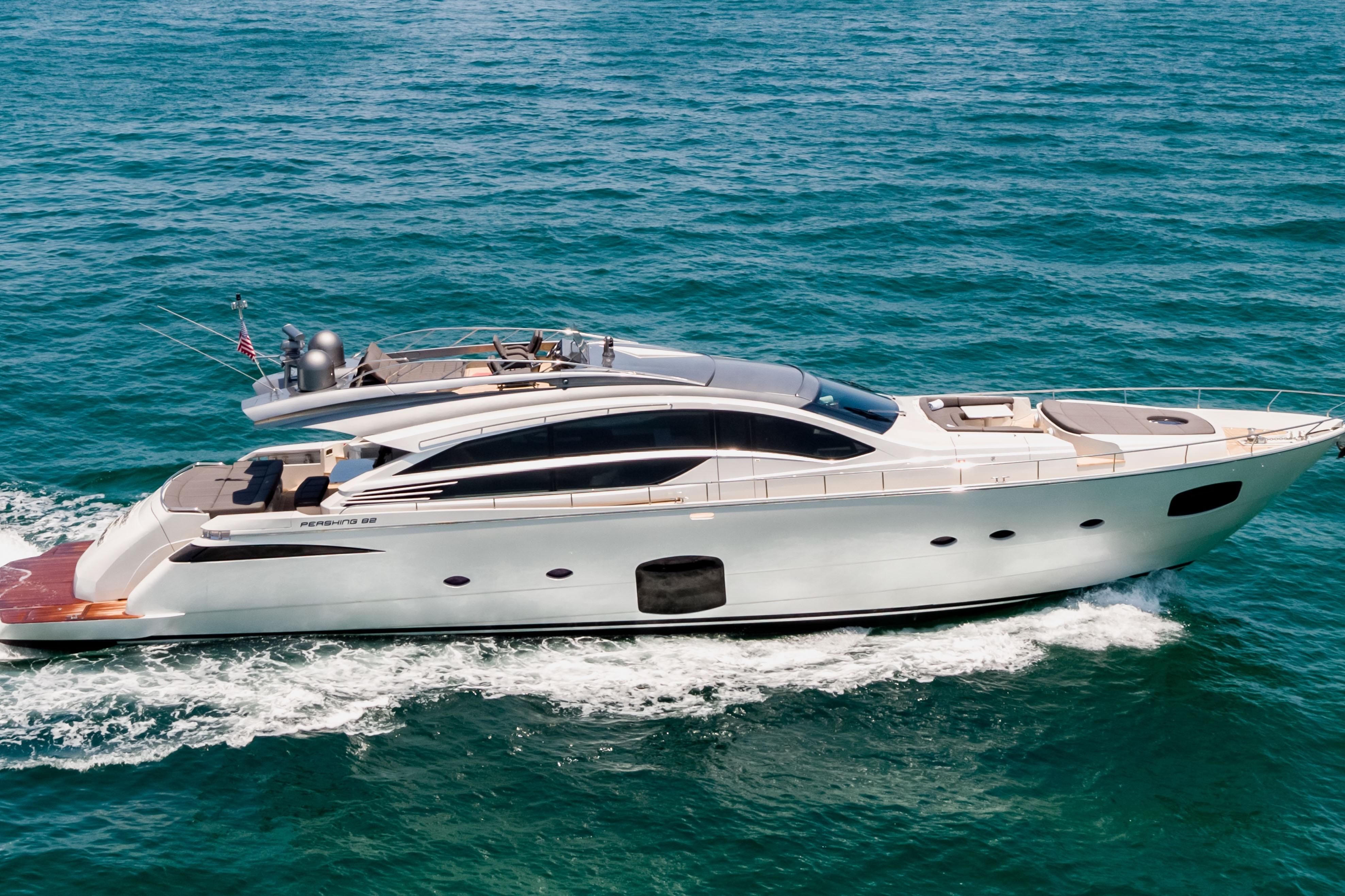 A sleek white luxury yacht cruises across turquoise water, leaving a foamy wake behind.