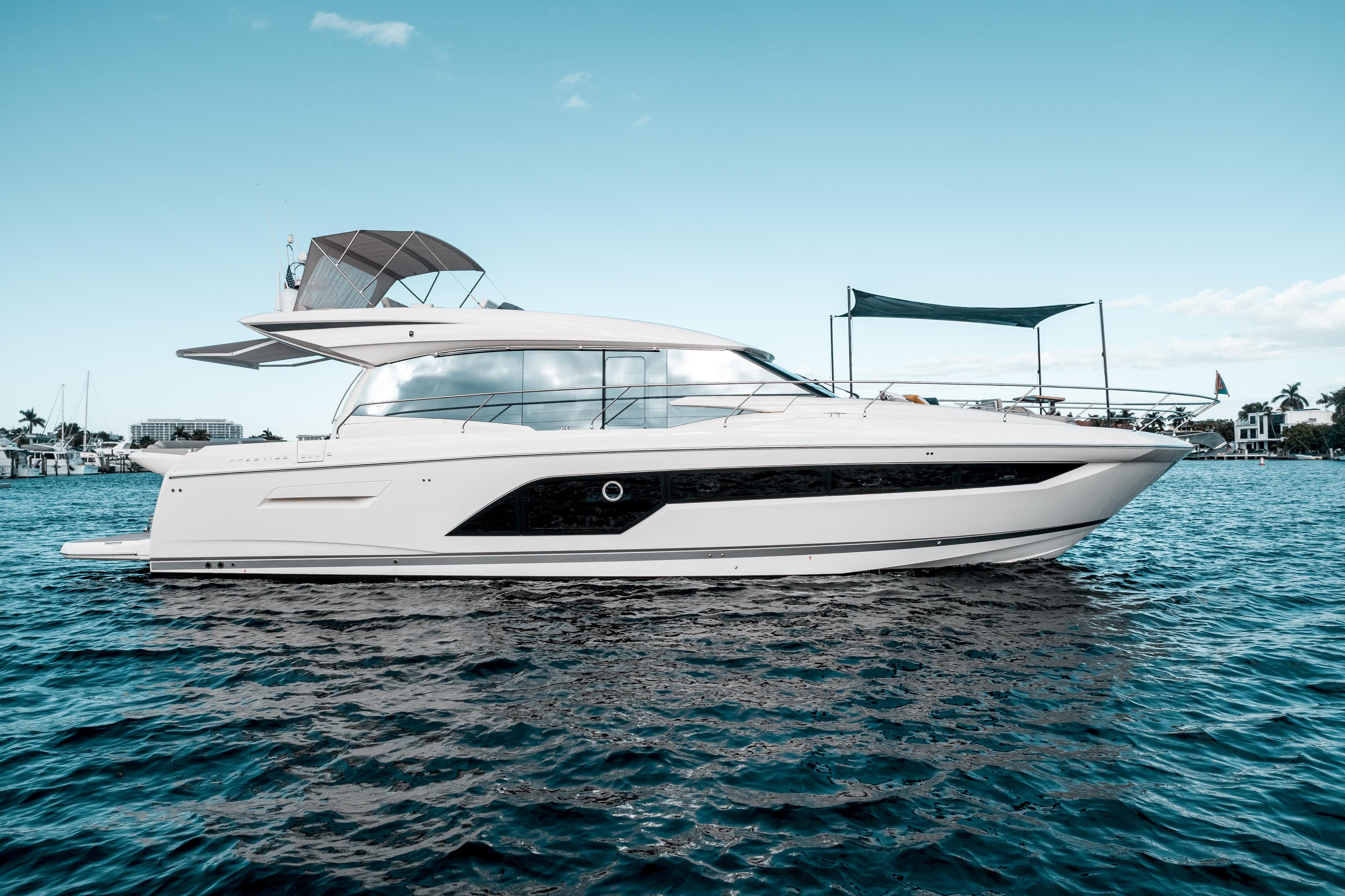 A sleek white luxury yacht with a black stripe floats on blue water under a clear sky.