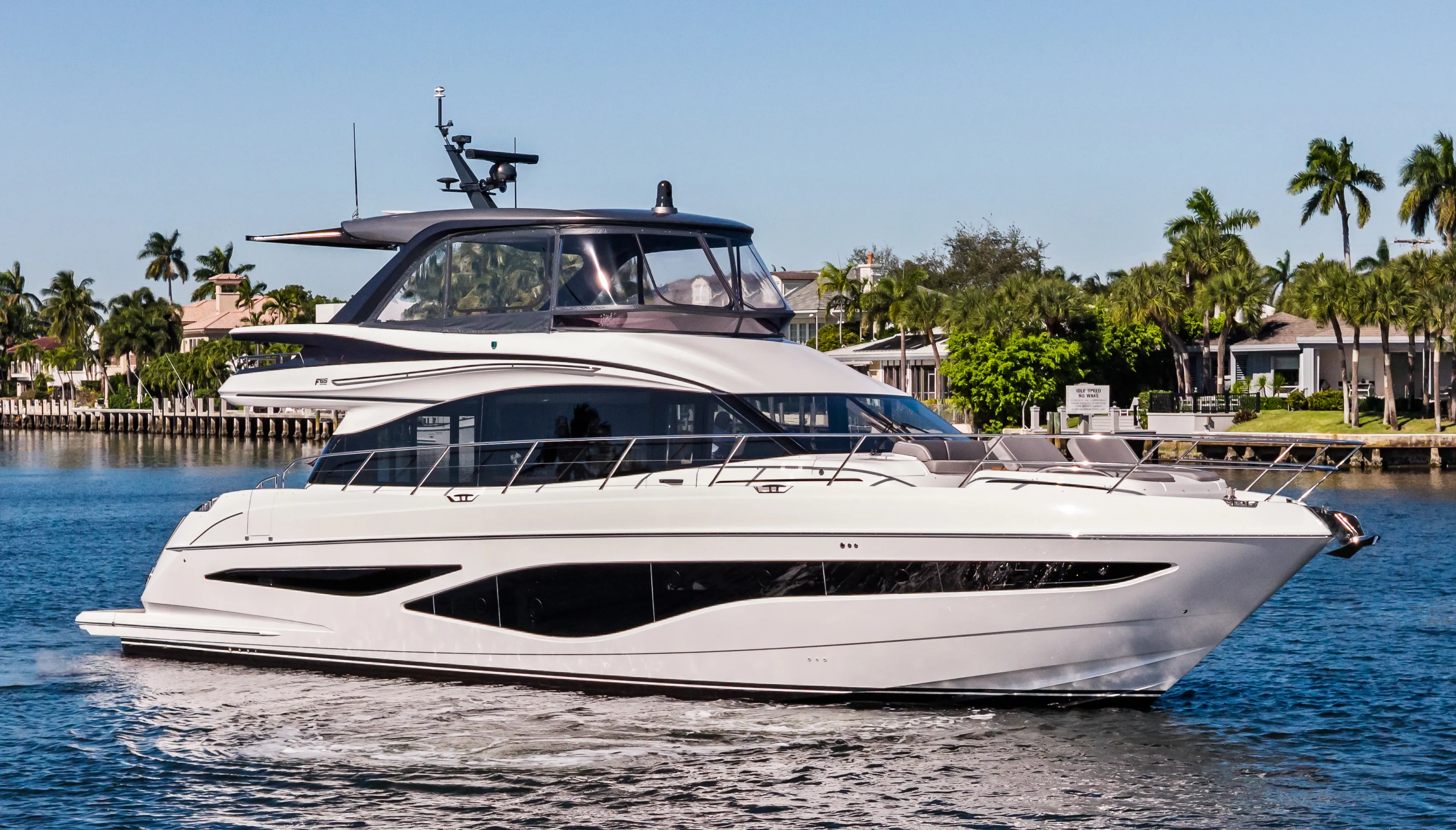 A sleek white luxury yacht with dark windows cruises on blue water.