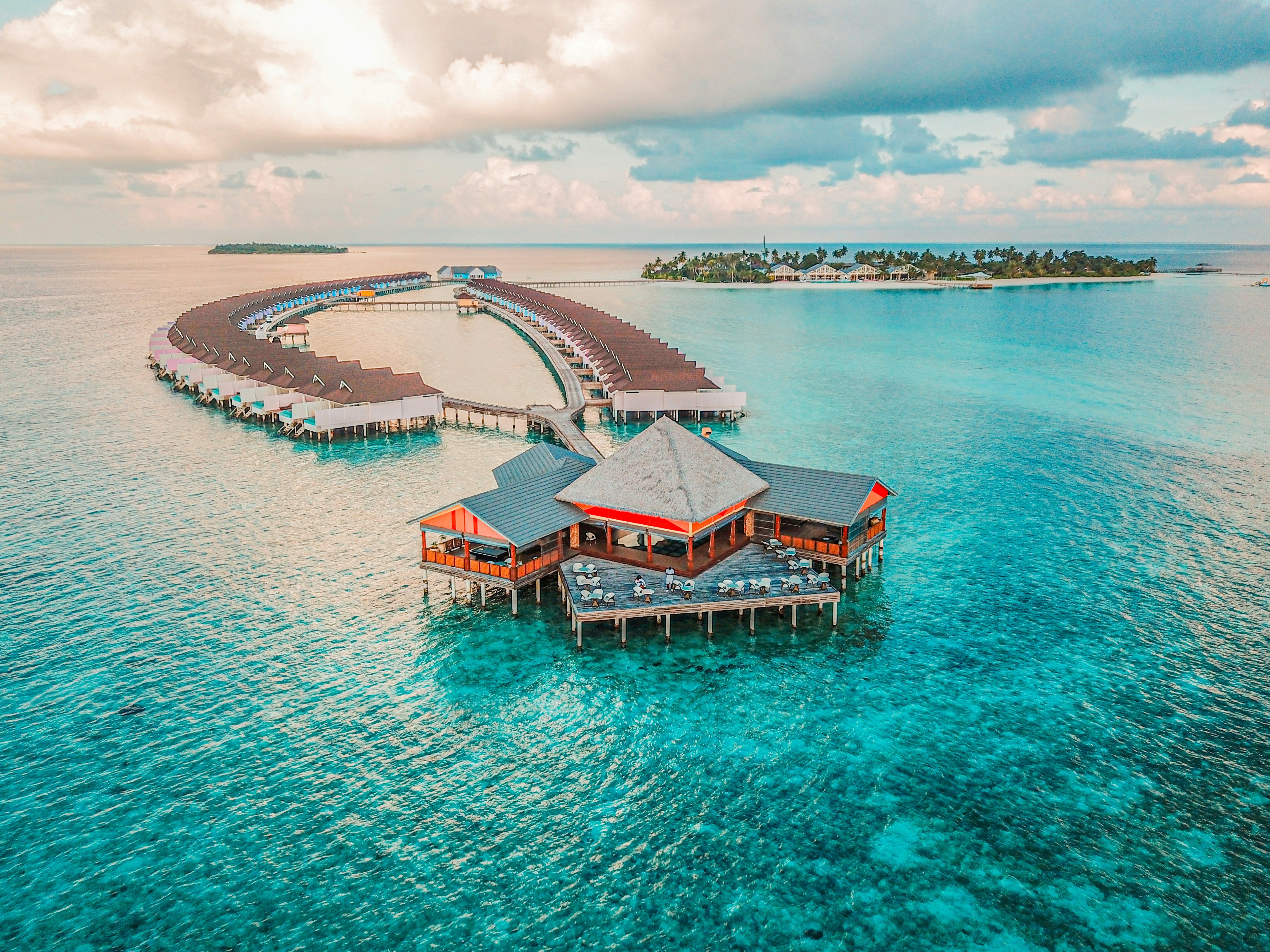 Aerial view of a luxurious overwater resort with bungalows over turquoise ocean water.