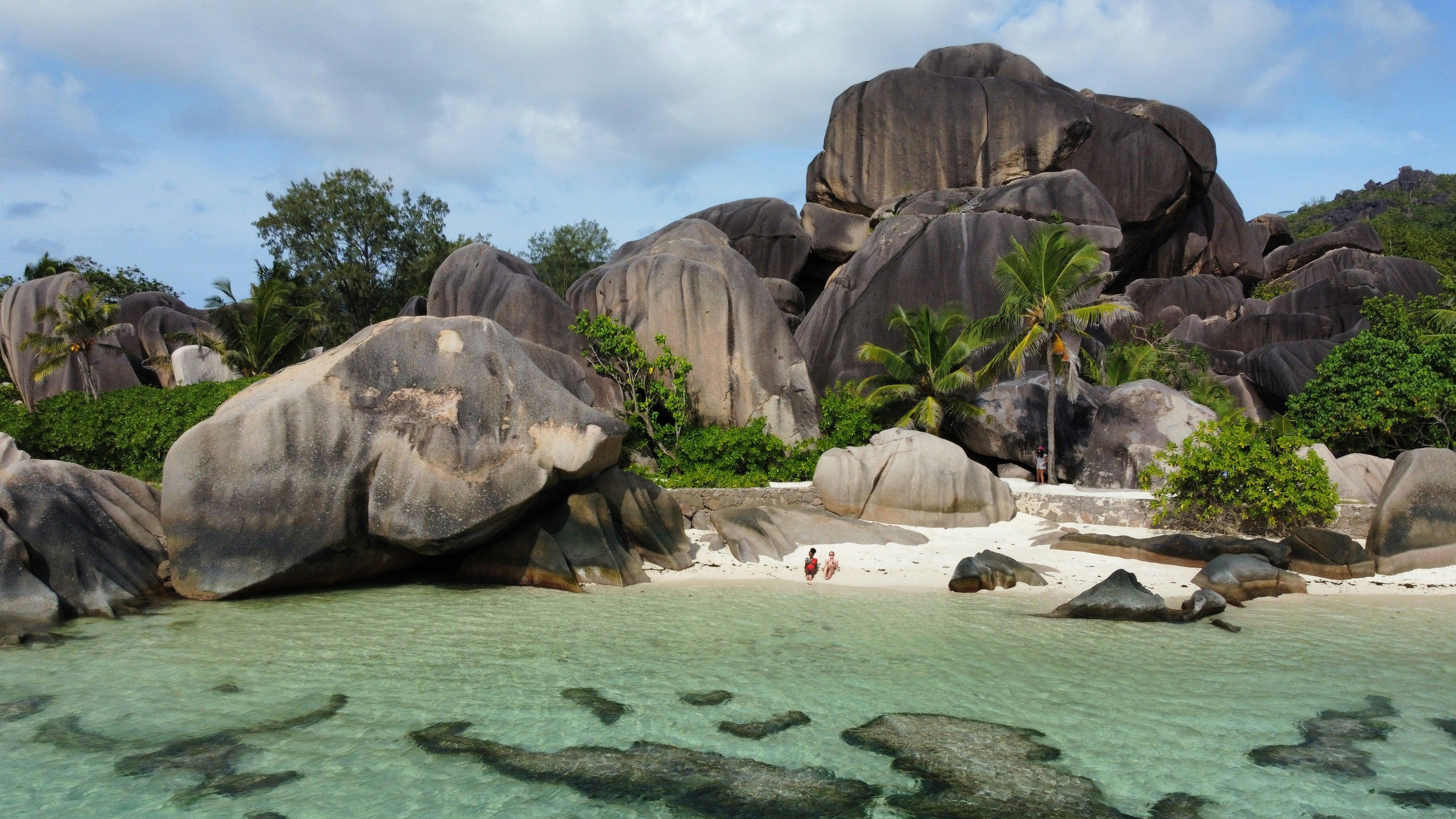 Granite boulders towering over a pristine white sand beach with clear turquoise water.