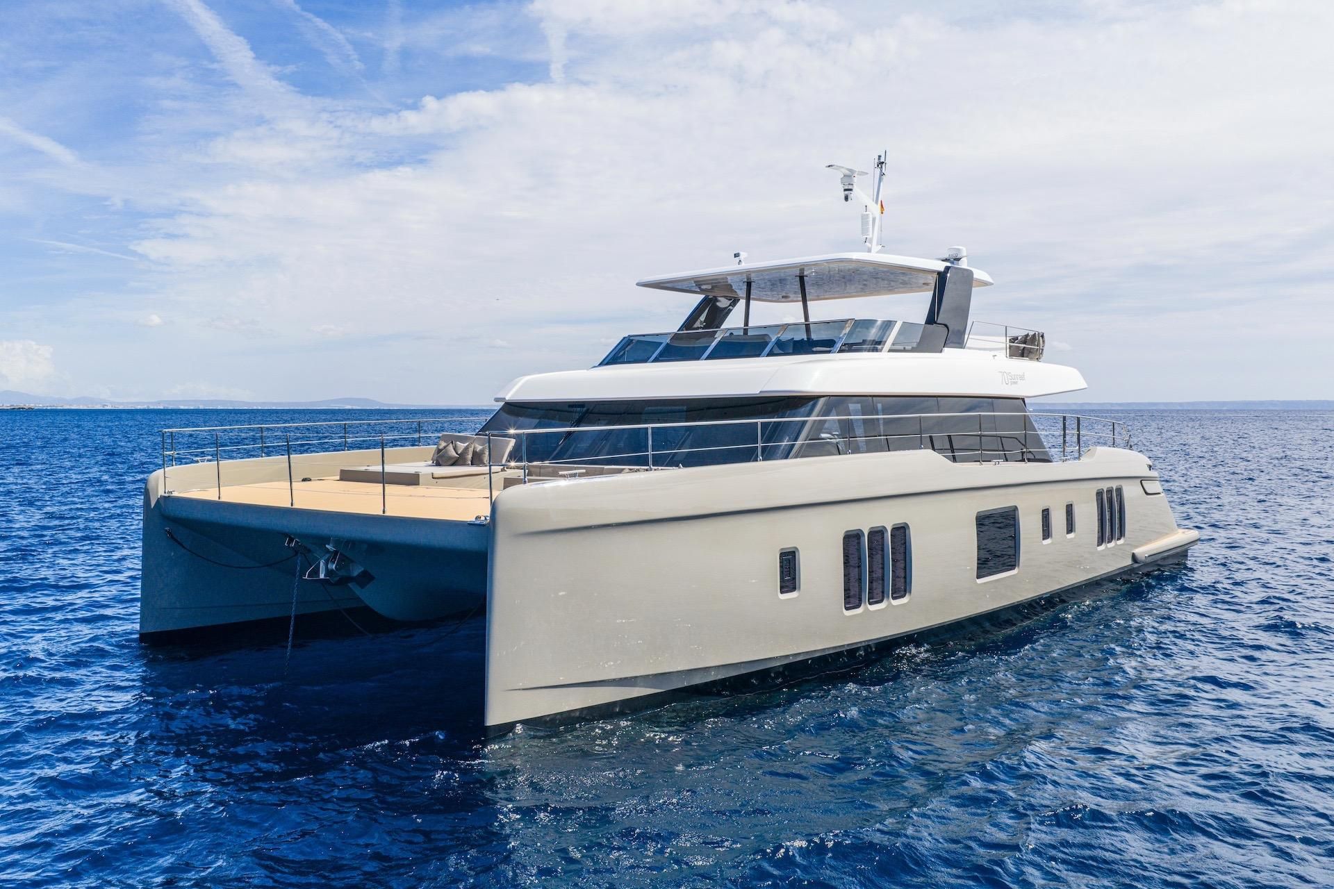 Large modern luxury catamaran yacht sailing on open blue water under a clear sky.
